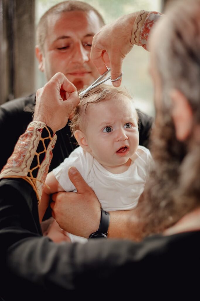 pexels-photo-12372467 A baby experiencing his first haircut held by his father inside a barber shop.